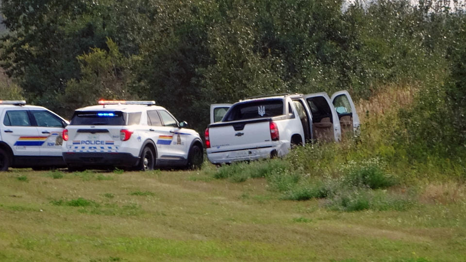 Police and investigators are seen at the side of the road outside Rosthern, Saskatchewan on Wednesday, Sept. 7, 2022. Canadian police arrested the second suspect in the stabbing deaths of 10 people in the province of Saskatchewan on Wednesday after a three-day manhunt during which they had found the body of his brother. (Kelly Geraldine Malone/The Canadian Press via AP)