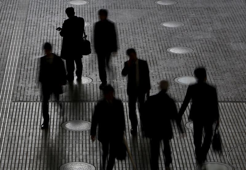 FILE PHOTO: People walk at an office building at a business district in Tokyo