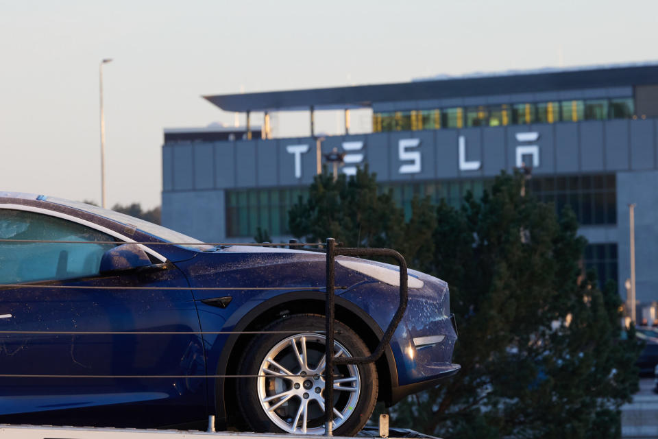 Ein Tesla-PKW steht am frühen Morgen vor der Tesla-Autofabrik auf einem Transporter. Ein Waldstück im Nord-Osten des Fabrikgeländes wird momentan im Rahmen eines Protestcamps besetzt. Tesla möchte dieses Waldstück für die Werkserweitung nutzen. - Copyright: picture alliance/dpa | Jörg Carstensen