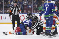 Linesmen Bevan Mills, back, and Tommy Hughes, right, try to separate Vancouver Canucks' Nils Hoglander (21) and Calgary Flames' Rasmus Andersson (4) as they get into scuffle after Andersson threw Hoglander to the ice during the third period of an NHL hockey game Tuesday, April 16, 2024, in Vancouver, British Columbia. (Darryl Dyck/The Canadian Press via AP)