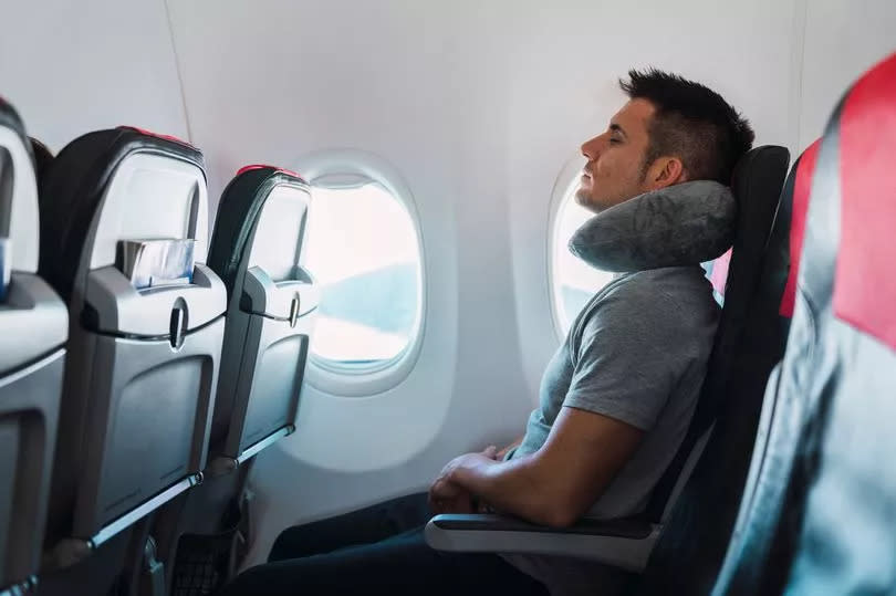 Man sleeping with neck pillow in airplane - stock photo