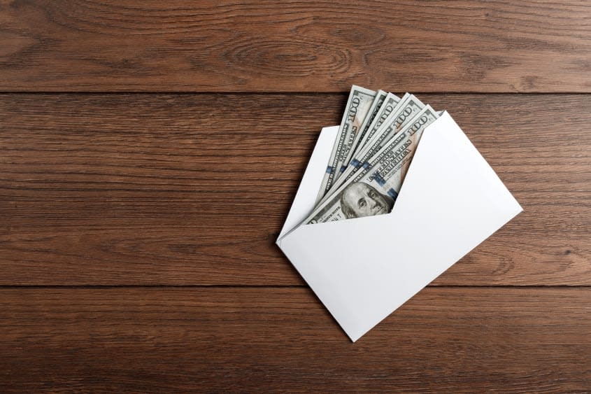 A photo of an envelope containing money on a wooden table