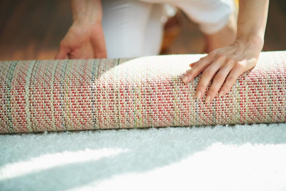 A rug being rolled up on hardwood flooring.