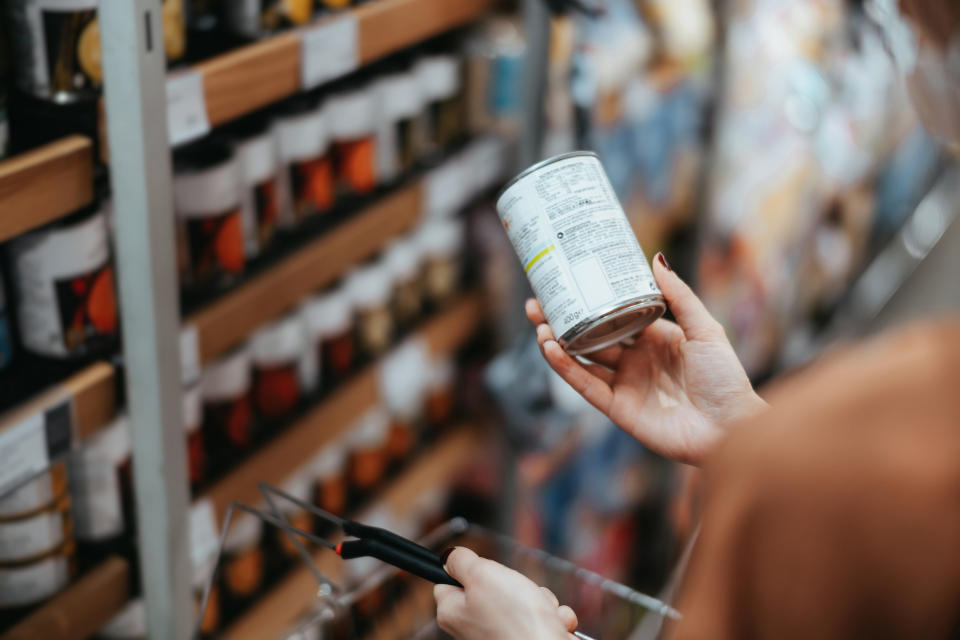 holding up the ingredients label of a canned good in a grocery store