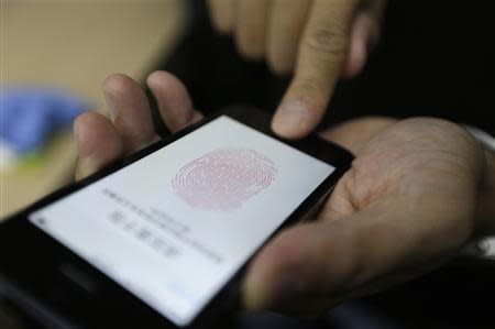 A journalist tests the the new iPhone 5S Touch ID fingerprint recognition feature at Apple Inc's announcement event in Beijing, in this September 11, 2013, file photo. REUTERS/Jason Lee