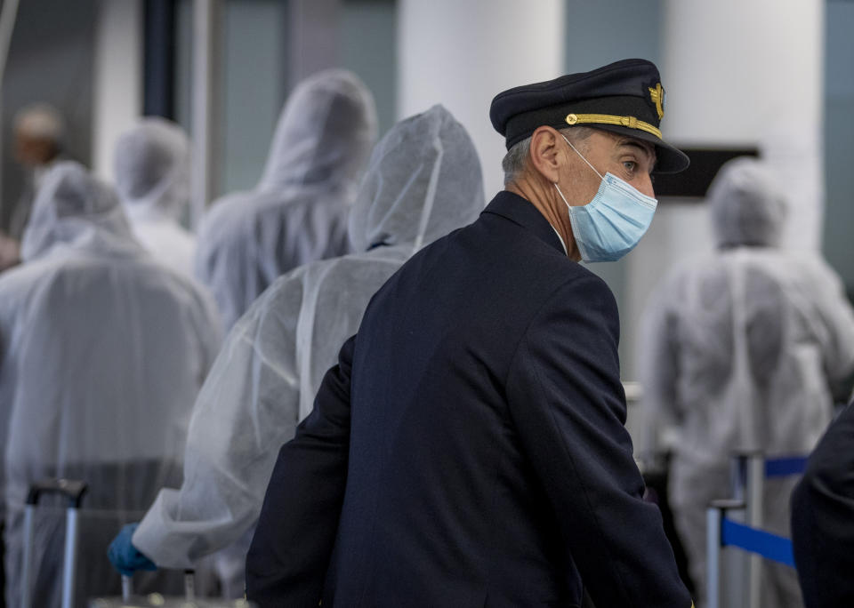 FILE - In this Saturday, April 18, 2020 file photo, a pilot and crew members of South African Airways go through the security check in Frankfurt, Germany. Questions are swirling in Africa and elsewhere over the financial wisdom of sustaining prestige carriers that have a tiny share of an aviation market that sees no recovery in sight as sub-Saharan Africa faces its first recession in a quarter-century amid coronavirus-related travel restrictions. (AP Photo/Michael Probst, File)