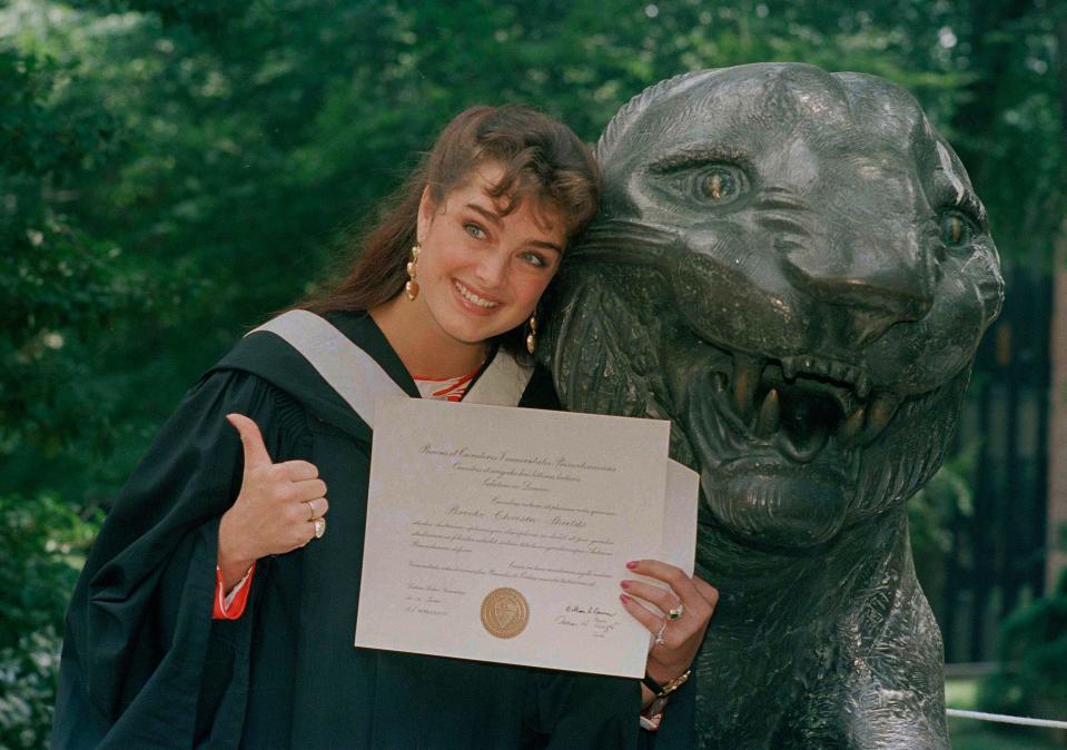 Brooke Shields gives the thumbs-up in her cap and gown as she shows her diploma during her graduation ceremony at Princeton University in Princeton, N.J. on June 9, 1987