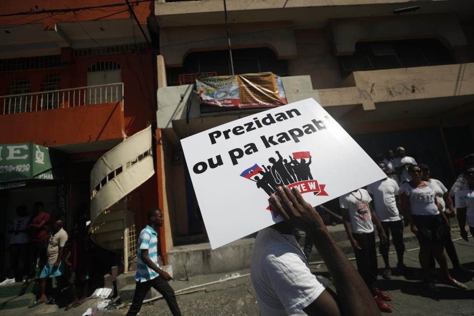 A protester carries the Creole message "Not your president" during a march led by the art community to demand the resignation of Haitian President Jovenel Moise in Port-au-Prince, Haiti, Sunday, Oct. 13, 2019. Protests have paralyzed the country for nearly a month, shuttering businesses and schools. (AP Photo/Rebecca Blackwell)