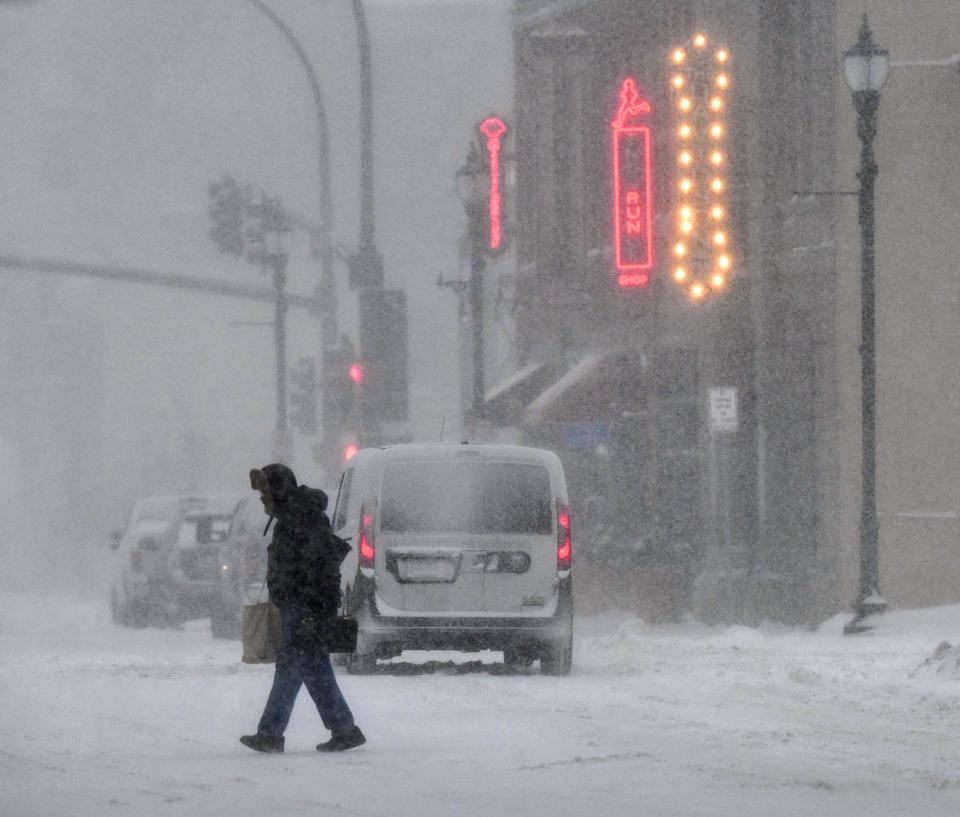 Heavy snow falls as people make their way home after work in downtown St. Cloud Friday, Jan. 17, 2020. 
