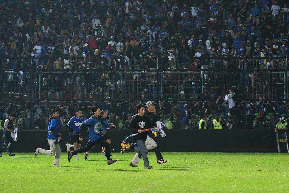Fans storm the pitch before the crush begins (AFP via Getty Images)
