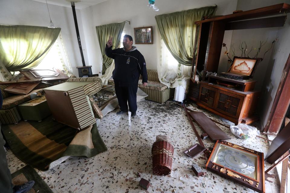 A Lebanese Shiite flashes a victory sign as he stands inside his living room, that was damaged when a deadly car bomb exploded Saturday evening, in the predominately Shiite town of Hermel, about 10 miles (16 kilometers) from the Syrian border in northeast Lebanon, Sunday, Feb. 2, 2014. A shadowy Lebanese Sunni extremist group late Saturday claimed responsibility for a suicide car bombing in Hermel, a stronghold of Lebanon's Shiite militant Hezbollah group, that killed several people in the latest attack linked to the war in neighboring Syria. (AP Photo/Hussein Malla)