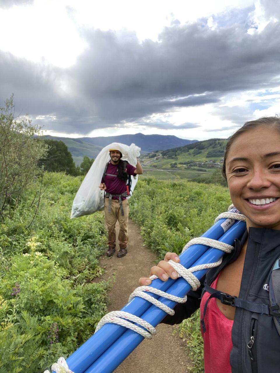 Gabriel Trujillo, hoisting a bag, with his fiancee, Roxanne Cruz-de Hoyos, foreground, in a field.