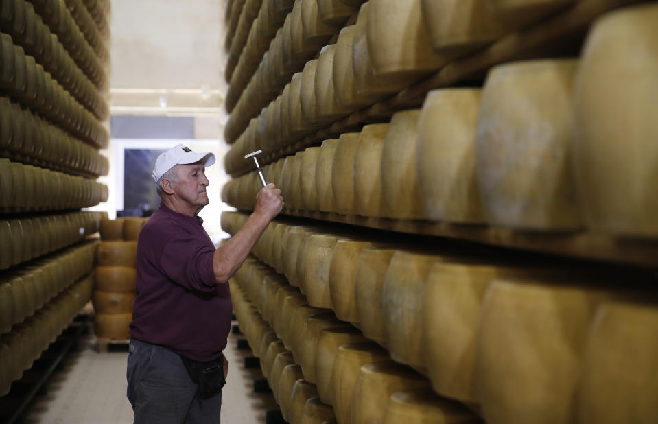 In this photo taken Tuesday, Oct. 8, 2019, Parmigiano Reggiano Parmesan cheese producer Gianni Bertinelli inspects wheels stored in Noceto, near Parma, Italy. U.S. consumers are snapping up Italian Parmesan cheese ahead of an increase in tariffs to take effect next week. The agricultural lobby Coldiretti on Friday, Oct. 11, 2019, said sales of both Parmigiano Reggiano and Grana Padano, aged cheeses defined by their territory of origin, have skyrocketed by 220% since the higher tariffs were announced one week ago. (AP Photo/Antonio Calanni)