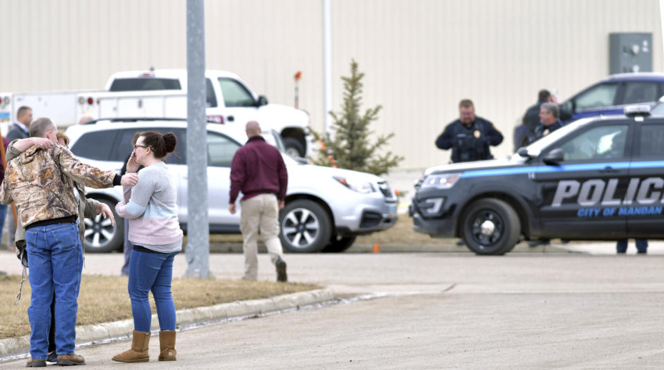 Family and friends console each other at the scene near the south side of the RJR Maintenance and Management building in Mandan, N.D., Monday, April 1, 2019. (Mike McCleary/The Bismarck Tribune via AP)