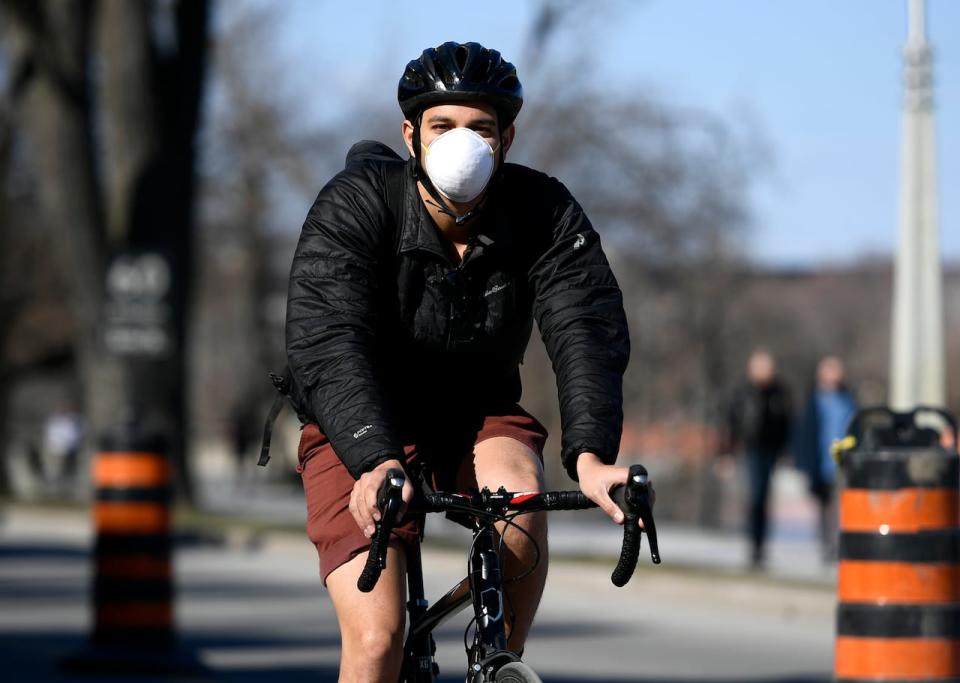 A cyclist wearing a mask rides along Queen Elizabeth Driveway in Ottawa, which has been partially closed to motor vehicle traffic during the COVID-19 pandemic, on Saturday, April 18, 2020. 