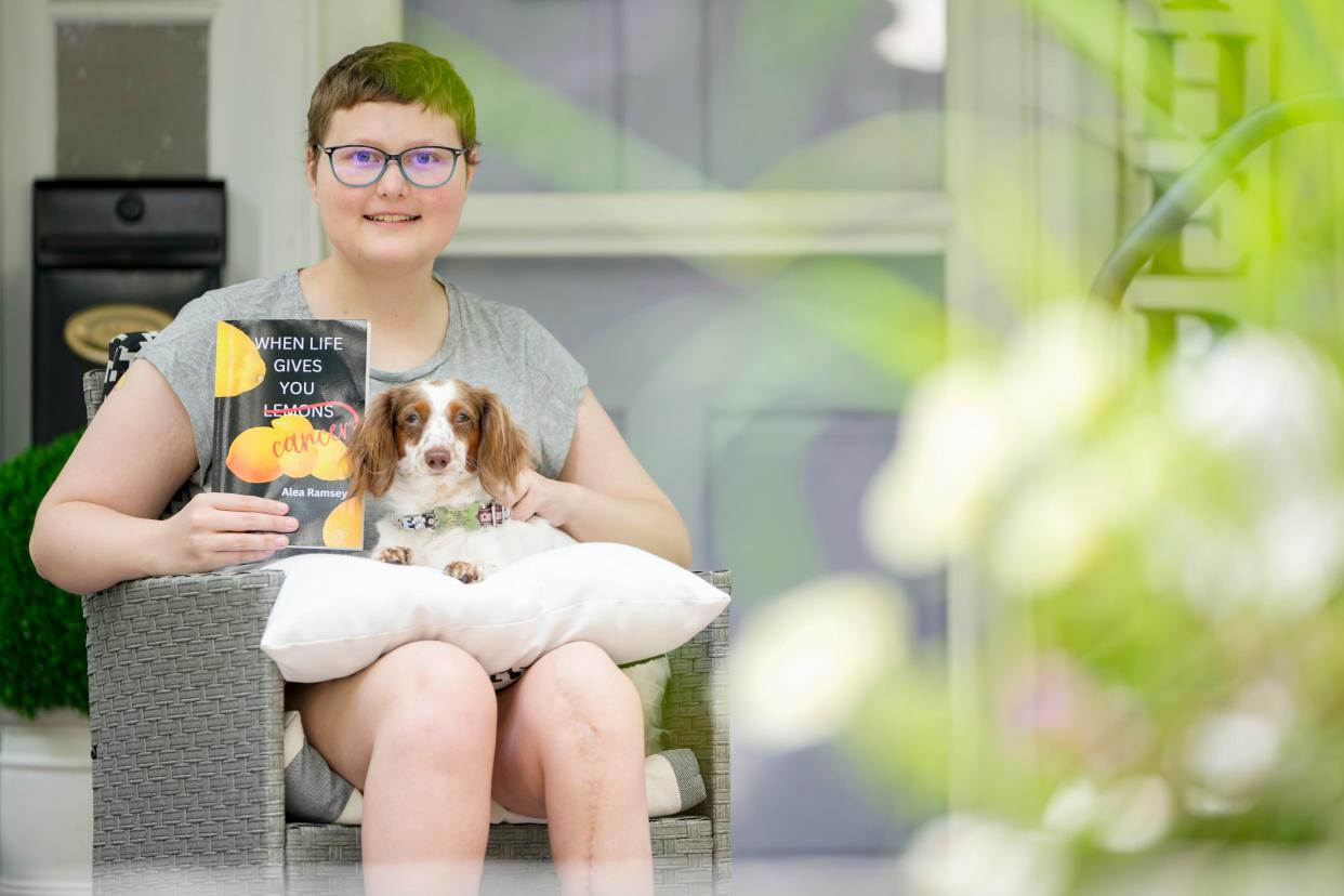 Sitting with her 1-year-old dachshund, Fiona, Upper Arlington High School senior Alea Ramsey, 18, holds her book titled “When Life Gives You Cancer” that talks about her experience with osteosarcoma. Ramsey was first diagnosed with the cancer when she was 13 and was recently diagnosed with the disease for an eighth time.