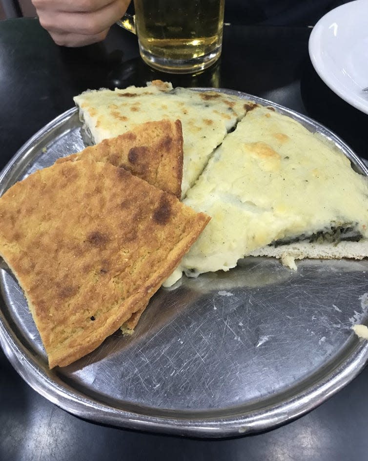 two white pizza slices on silver tray with faina chickpea pancake on top of it
