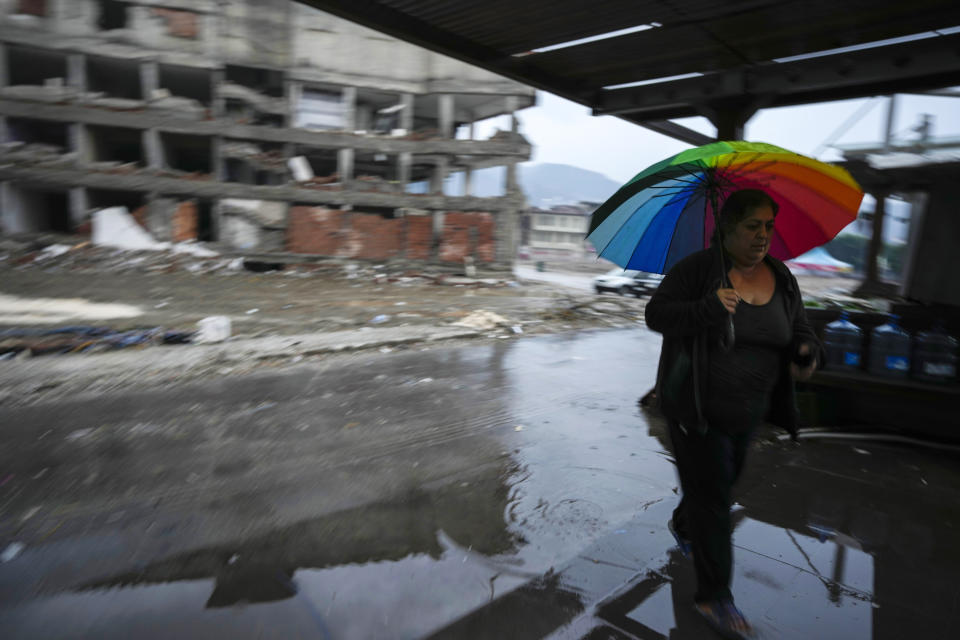 A woman holding an umbrella walks amid destroyed buildings in Antakya, southern Turkey, Friday, Jan. 12, 2024. A year after a powerful earthquake struck on Feb. 6, 2023, many in the stricken region are struggling to rebuild lives. (AP Photo/Khalil Hamra)