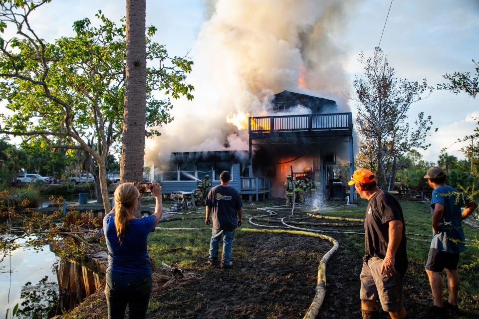 A woman, left, FaceTimes the homeowners of a home in Suwannee, Fla. so they can see the fire that is blazing through their home after neighbors and others had tried to control the flames on Thursday, Aug. 31, 2023.