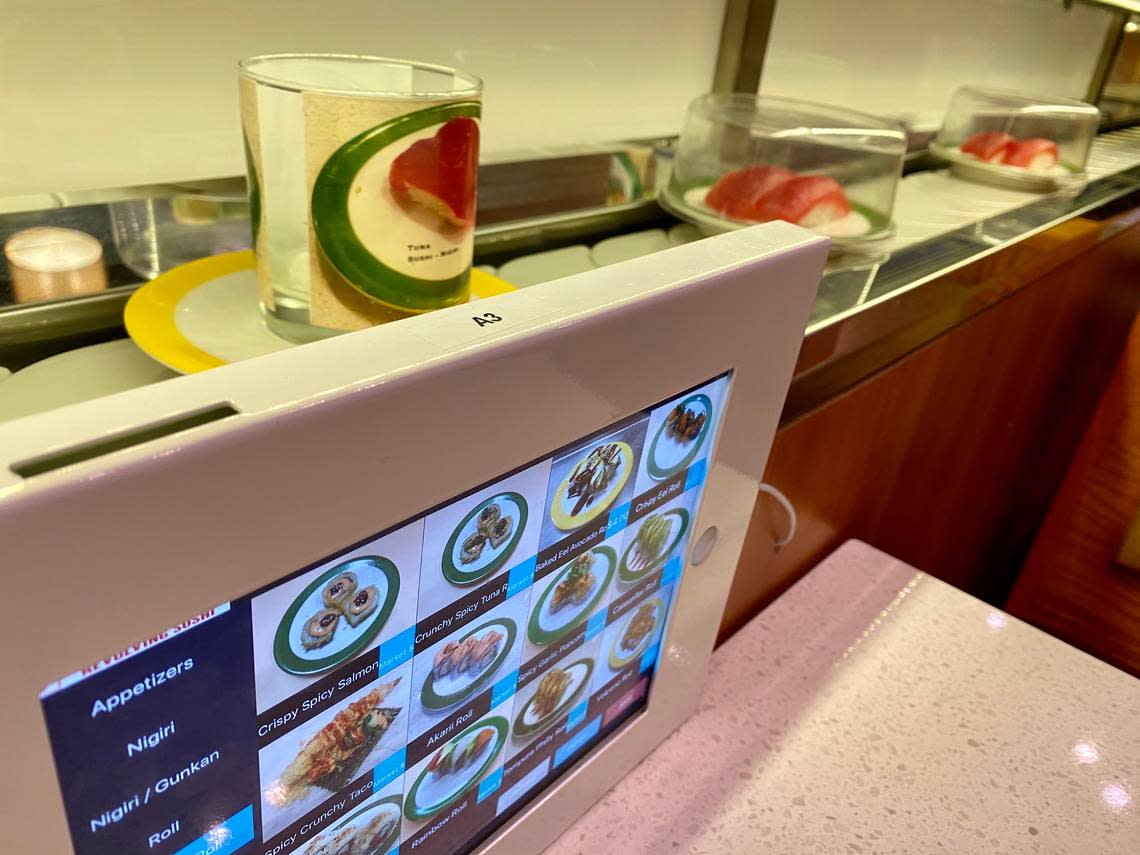 A conveyor belt rotates sushi past tables equipped with iPads at Akarii Revolving Sushi.
