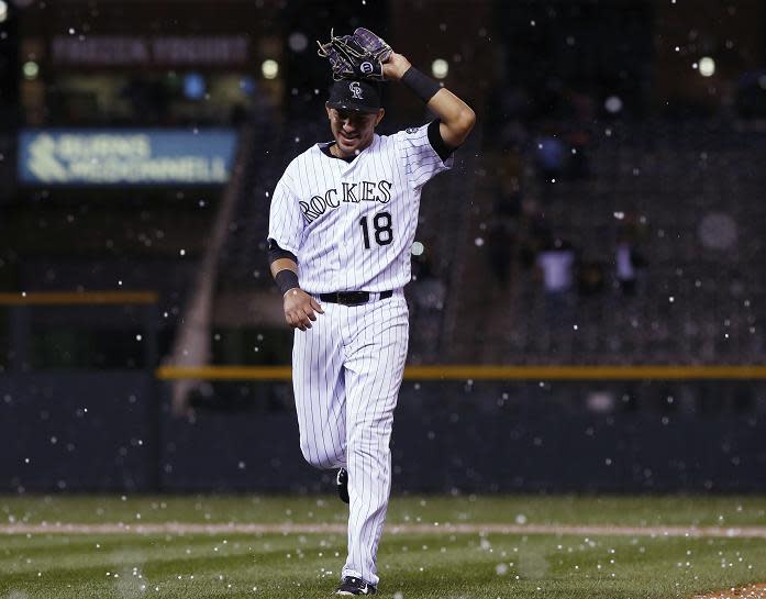 Rockies shortstop Cristhian Adames uses his glove to shield his head during a hailstorm at Coors Field. (AP)