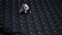 A worker disinfects seats prior to the start of the second round of the 2020 Atlantic 10 men's basketball tournament at Barclays Center on March 12, 2020 in the Brooklyn borough of New York City. The tournament was canceled amid growing concerns of the spread of Coronavirus (COVID-19). (Photo by Mike Lawrie/Getty Images)