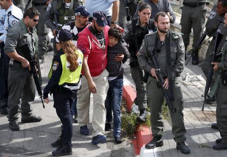 Israeli police lead away a Palestinian minor (C) they said stabbed an Israeli security guard in Pisgat Zeev, which lies on occupied land that Israel annexed to Jerusalem after the 1967 Middle East war, November 10, 2015. REUTERS/Ammar Awad