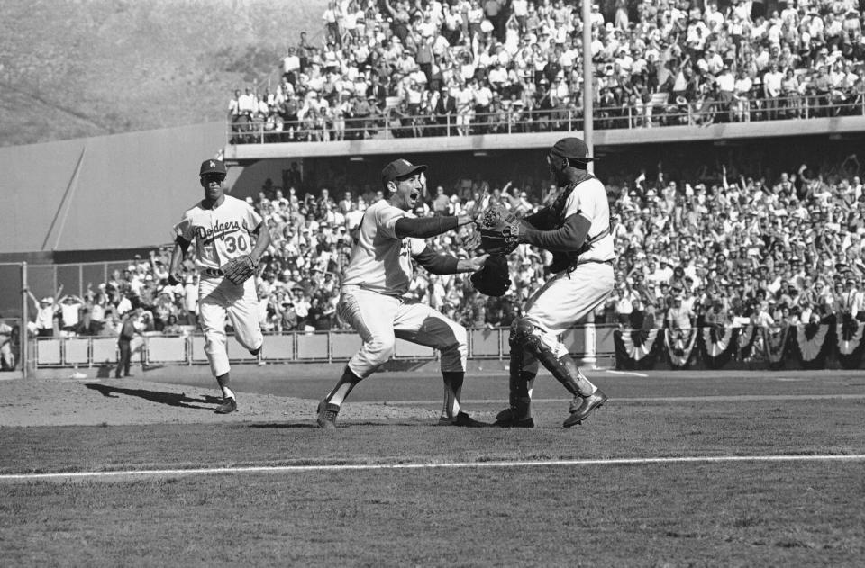 Dodgers pitcher Sandy Kaufax, left, and catcher John Roseboro celebrate after beating the New York Yankees.