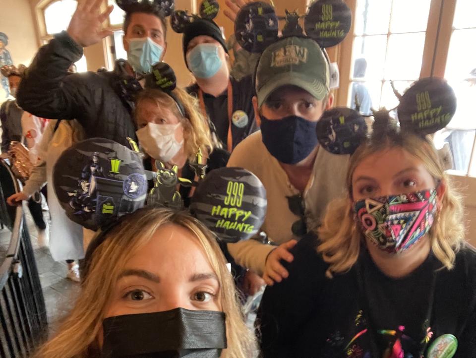 group of people wearing matching mickey ears posing for a selfie at disneyland