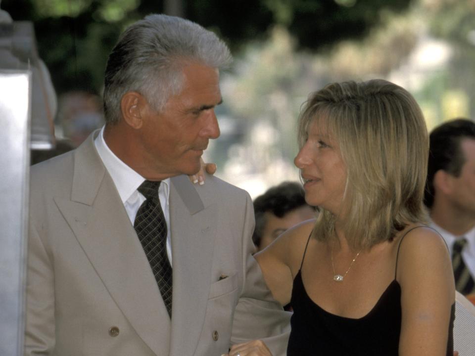 James Brolin, in a gray suit, sits next to Barbra Streisand, in a black dress, during a 1998 outdoor ceremony.