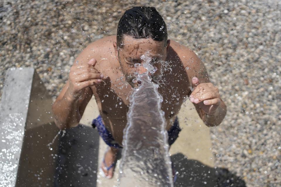 A man cools himself under a shower at a beach in Loutraki, about 82 kilometres (51 miles) west of Athens, Greece, Thursday, July 20, 2023. Heat in Greece is expected to grow worse in the next five days, approaching 44 Celsius (111 Fahrenheit) and the country will face one more heatwave episode by the end of July, meteorologists warn. (AP Photo/Thanassis Stavrakis)