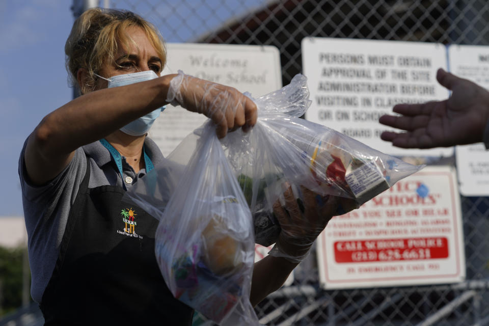 Los Angeles Unified School District food service worker Marisel Dominguez, left, distributes free school lunches on Friday, July 16, 2021, at the Liechty Middle School in Los Angeles. Flush with cash from an unexpected budget surplus, California is launching the nation's largest statewide universal free lunch program. When classrooms open for the fall term, every one of California's 6.2 million public school students will have the option to eat school meals for free, regardless of their family's income. (AP Photo/Damian Dovarganes)