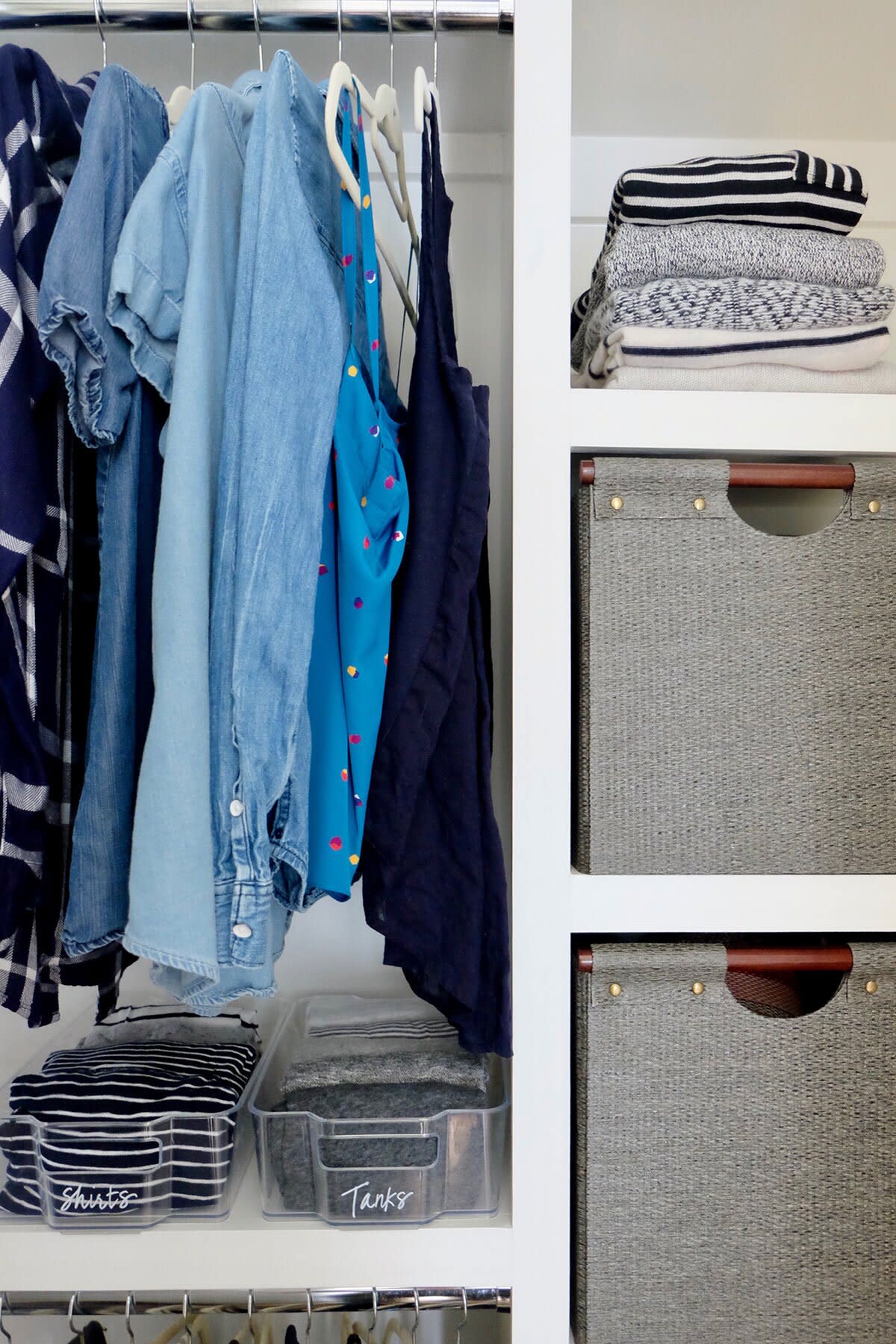 Organized Closet With Clothes Hanging, Sweaters Folded on Shelf, and Labeled Bins for Shirts