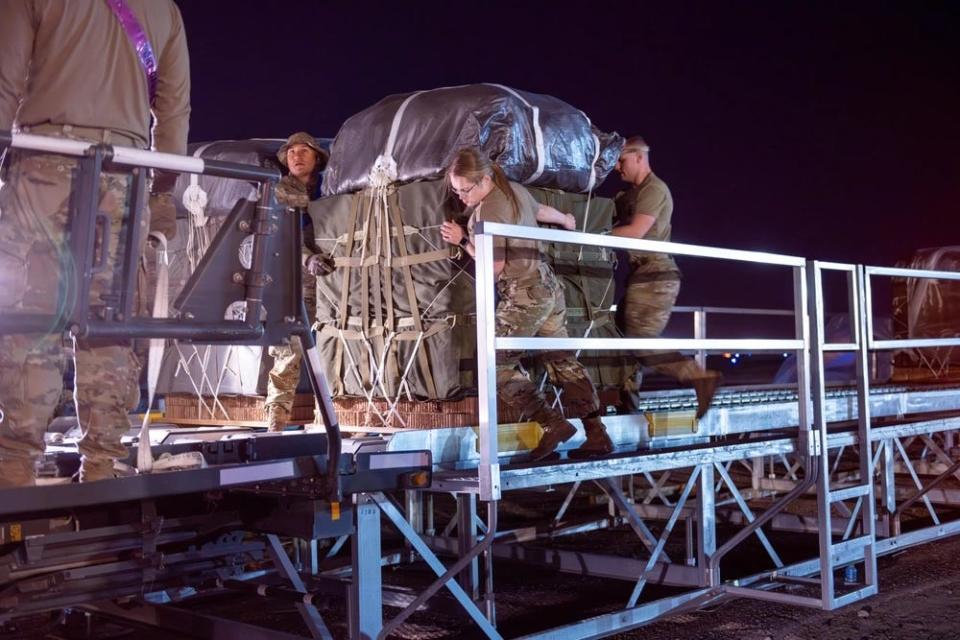 US Air Force Aerial Port Airmen and US Army parachute riggers usher in pallets of humanitarian aid destined for Gaza onto a K-loader.