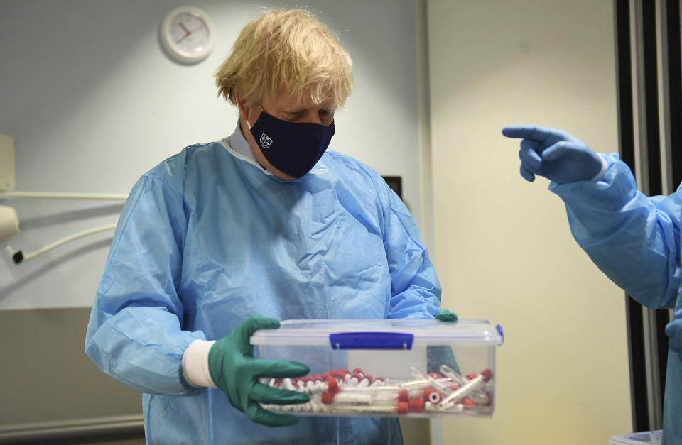 Britain's Prime Minister Boris Johnson holds samples, at the Lighthouse Laboratory, used for processing polymerase chain reaction (PCR) samples for coronavirus, during a visit to the Queen Elizabeth University Hospital campus in Glasgow on his one day visit to Scotland, Thursday, Jan. 28, 2021. Johnson is facing accusations that he is not abiding by lockdown rules as he makes a trip to Scotland on Thursday to laud the rapid rollout of coronavirus vaccines across the United Kingdom. (Jeff Mitchell/Pool Photo via AP)