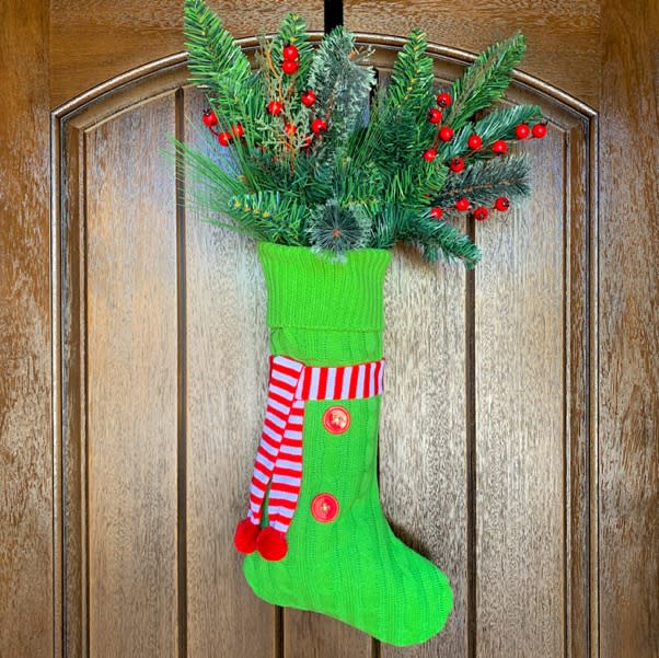 green knit stocking full of faux greenery (The Frugal Girls)