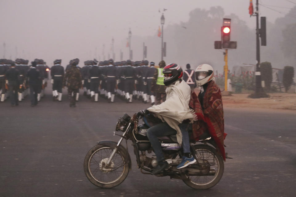 In this Wednesday, Dec. 26, 2018, photo, a motorcyclist rides wearing pollution masks in New Delhi, India. Authorities have ordered fire services to sprinkle water from high rise building to settle dust particles and stop burning of garbage and building activity in the Indian capital as the air quality hovered between severe and very poor this week posing a serious health hazard for millions of people. (AP Photo/Manish Swarup)