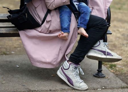 A Syrian migrant holds the child in Kanizsa, Serbia 27 July, 2015. REUTERS/Laszlo Balogh