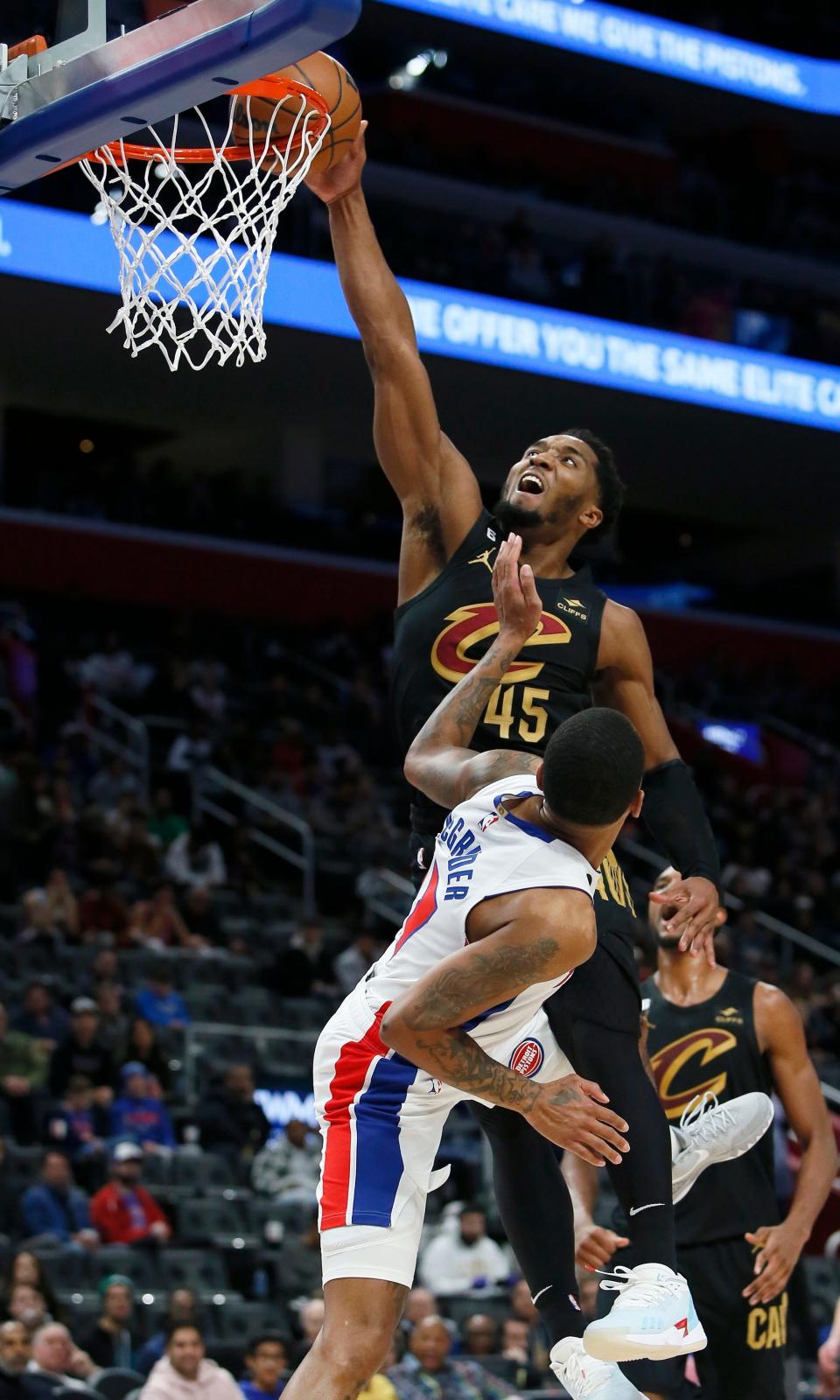 Cavaliers guard Donovan Mitchell (45) goes over Pistons guard Rodney McGruder (17) to dunk during the second half Sunday, Nov. 27, 2022, in Detroit. The Cavaliers won 102-94.