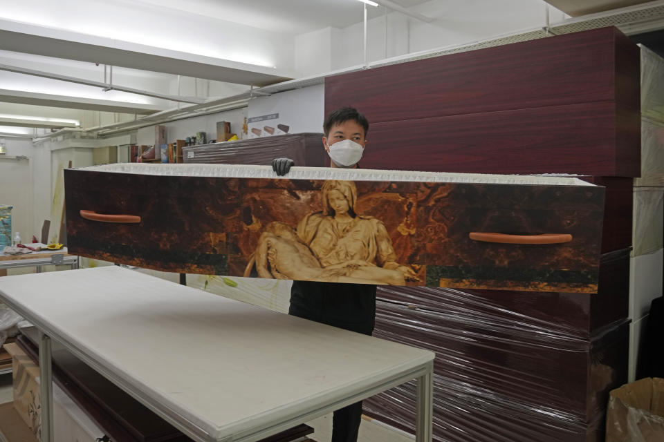 A worker lifts up a paper coffin at the factory of LifeArt in Hong Kong, Friday, March 18, 2022. Hong Kong is running short of coffins during its deadliest outbreak of the coronavirus pandemic. LifeArt, a company in Hong Kong is trying to make an alternative, cardboard coffin, which it says is environmentally-friendly. (AP Photo/Kin Cheung)