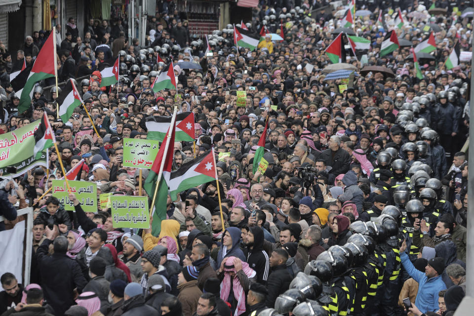 Protesters carry Jordanian and Palestinian flags and slogans during a protest against the Middle East peace plan proposed by U.S. President Donald Trump, in the center of Amman, Jordan, Friday, Jan. 31, 2020. (AP Photo/Raad Adayleh)