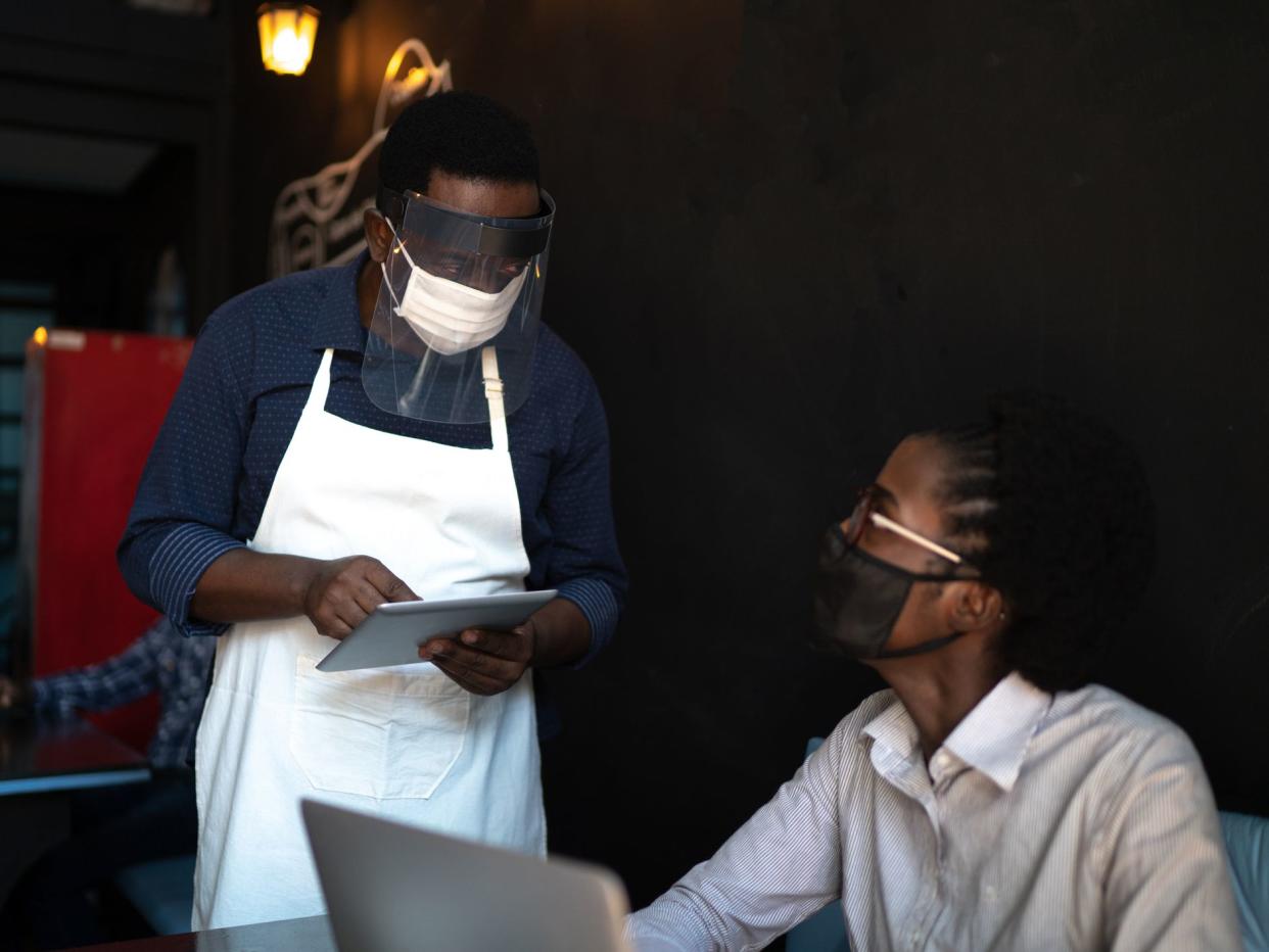 Waiter taking client's order, using a digital tablet in a restaurant