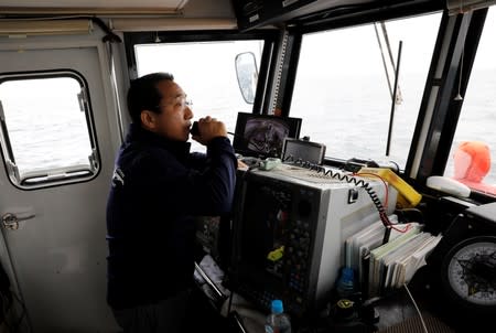 Whale-watching boat captain Masato Hasegawa speaks with other boats in order to look for whales in the sea near Rausu