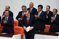 Ministers applaud Turkish Prime Minister Recep Tayyip Erdogan, front, at the parliament in Ankara, Turkey, Wednesday, April 23, 2014. Erdogan has issued a conciliatory message to Armenians on the eve of the anniversary of the massacre of Armenians almost a century ago, calling the events of World War I "our shared pain." In a statement released Wednesday in nine languages _ including Armenian _ Erdogan said he hoped Armenians who lost their lives are in peace and expressed condolences to their descendants.(AP Photo)