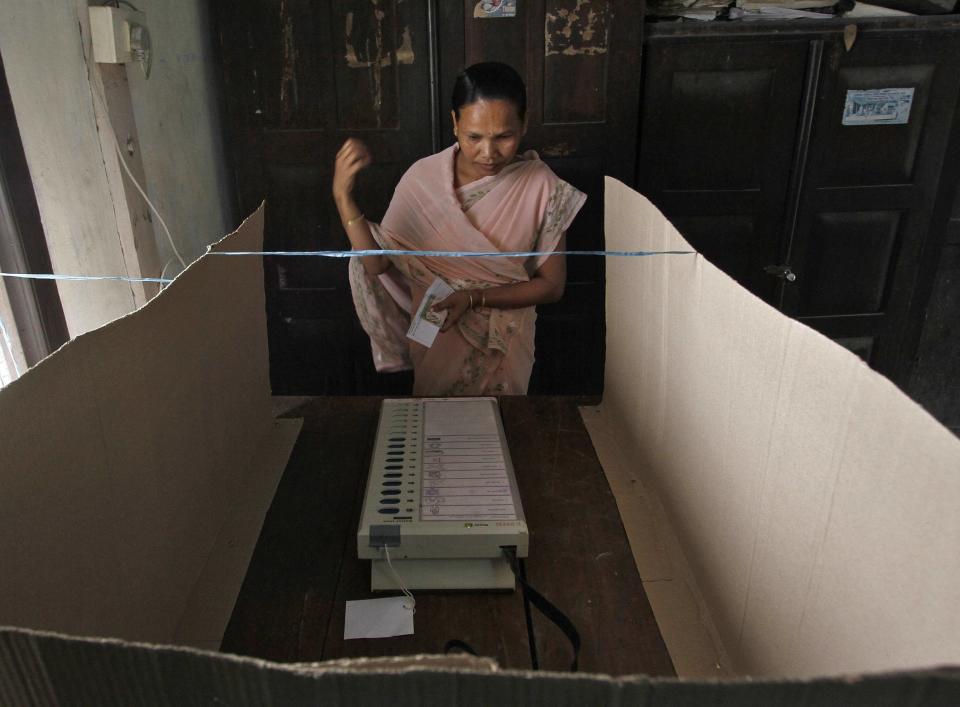 A woman prepares to cast her vote using an electronic voting machine inside a polling booth at Dhekiajuli in Sonitpur district in the northeastern Indian state of Assam April 7, 2014. (REUTERS/Utpal Baruah)