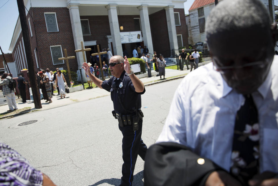 A police officer clears the area after a bomb threat came in as parishioners exit a memorial service at Morris Brown AME Church for the nine people killed Wednesday during a prayer meeting inside a historic black church in Charleston, S.C., Thursday, June 18, 2015. (AP Photo/David Goldman)