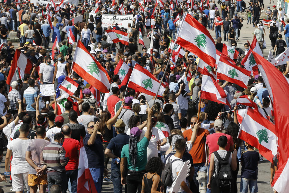 Anti-government protesters hold Lebanese national flags as shout slogans during a protest in downtown Beirut, Lebanon, Saturday, June 6, 2020. Hundreds of Lebanese demonstrators gathered in central Beirut Saturday, hoping to reboot nationwide anti-government protests that began late last year amid an unprecedented economic and financial crisis. (AP Photo/Bilal Hussein)