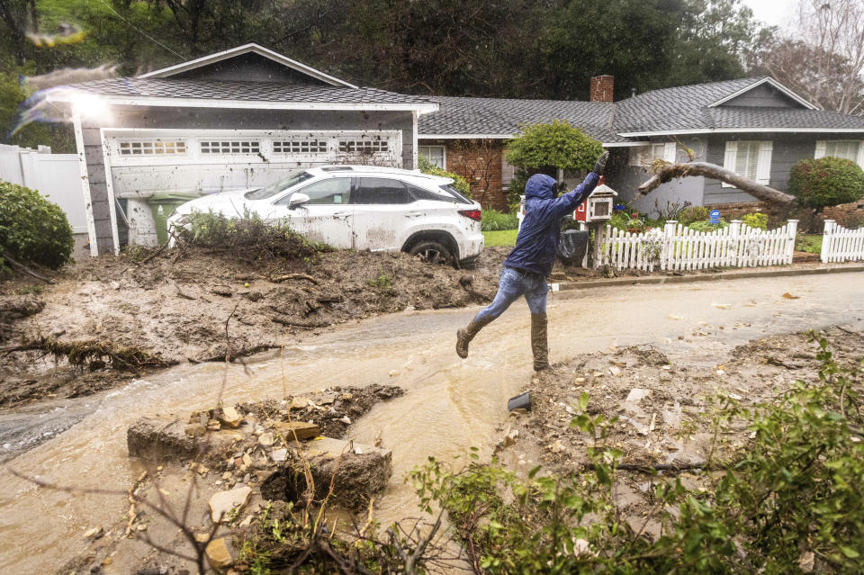 Jeffrey Raines clears debris from a mudslide at his parent's home during a rainstorm, Monday, Feb. 5, 2024, in Los Angeles. The second of back-to-back atmospheric rivers took aim at Southern California, unleashing mudslides, flooding roadways and knocking out power as the soggy state braced for another day of heavy rains. (AP Photo/Ethan Swope)