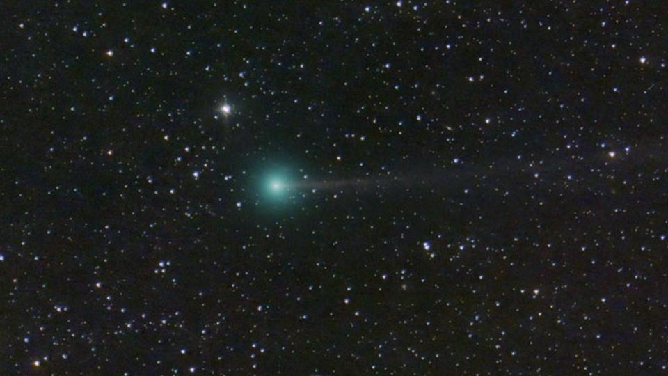 An image of star-filled space with a green comet shooting through the field of view