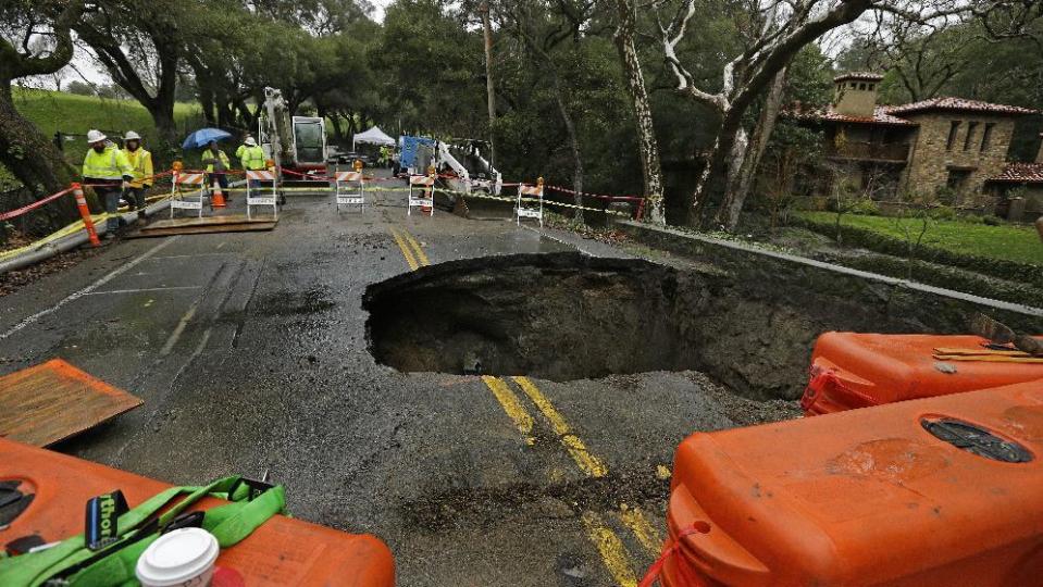 Contractors survey a 72-inch sinkhole Wednesday, Jan. 18, 2017, in Orinda, Calif. The city council of Orinda declared a State of Emergency Tuesday night because of a large sinkhole caused by last week's wet weather. Repairs will take at least four weeks, as the San Francisco Bay Area is being hit with a new series of rain storms. (AP Photo/Ben Margot)